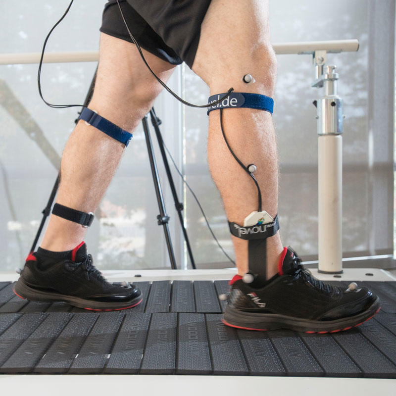 Photo of legs walking on planked treadmill while wearing sensor equipment